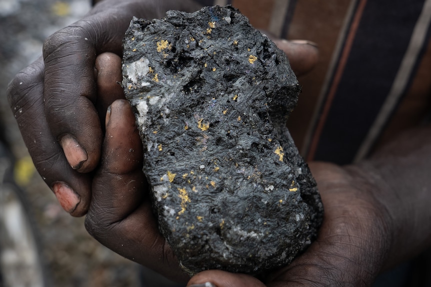 A close up photo of a mining rock with gold in it.