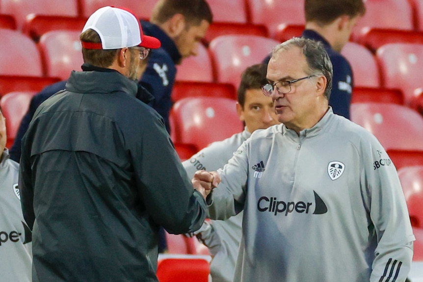 Two football managers bump fists in recognition after a Premier League match at Anfield.