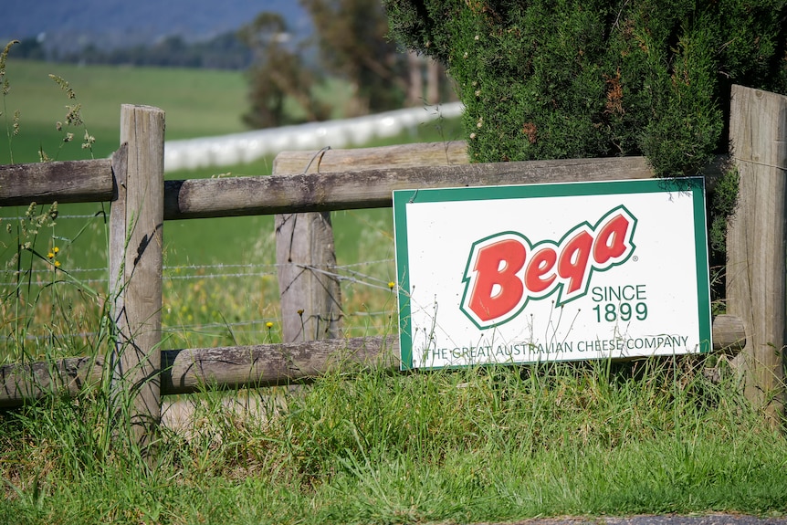 a sign of Bega cheese on a fence with green grass around