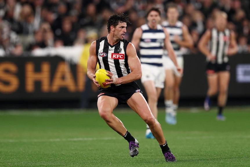 Scott Pendlebury takes a step while holding the ball