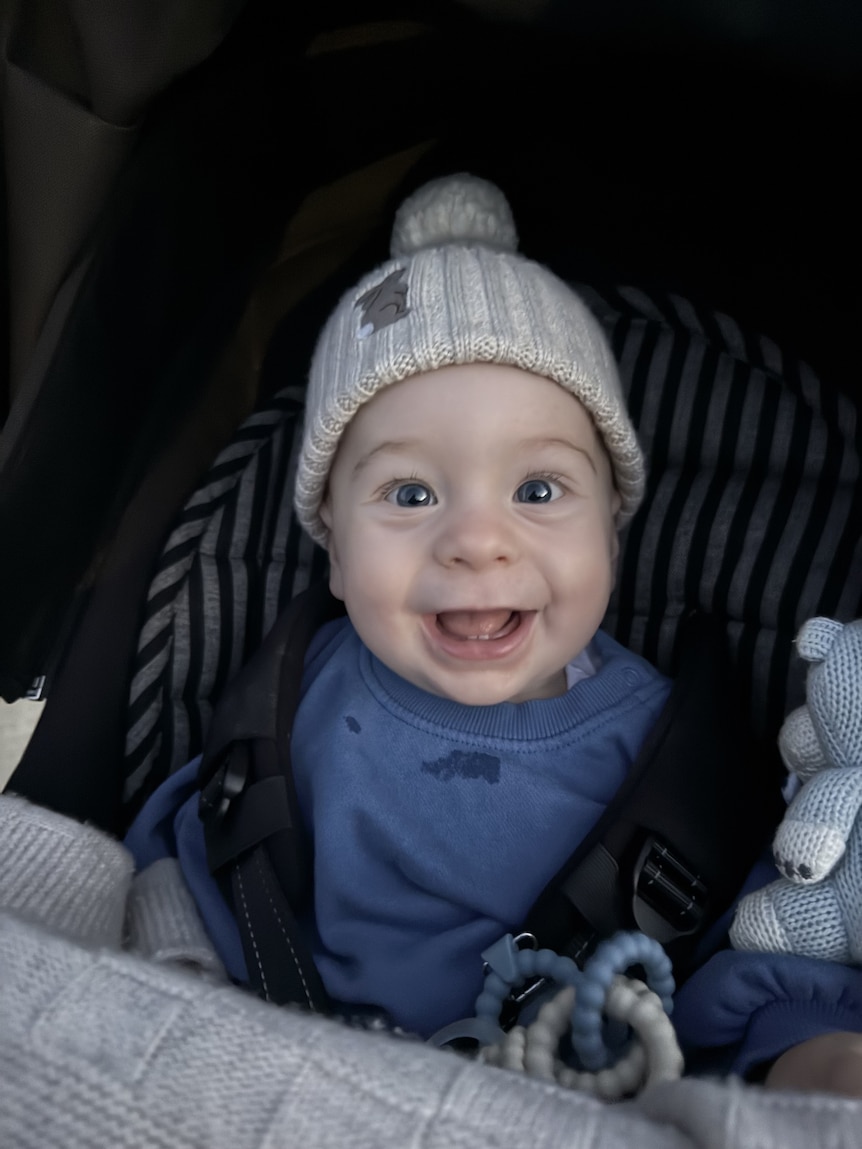 A smiling baby boy sitting in a pram