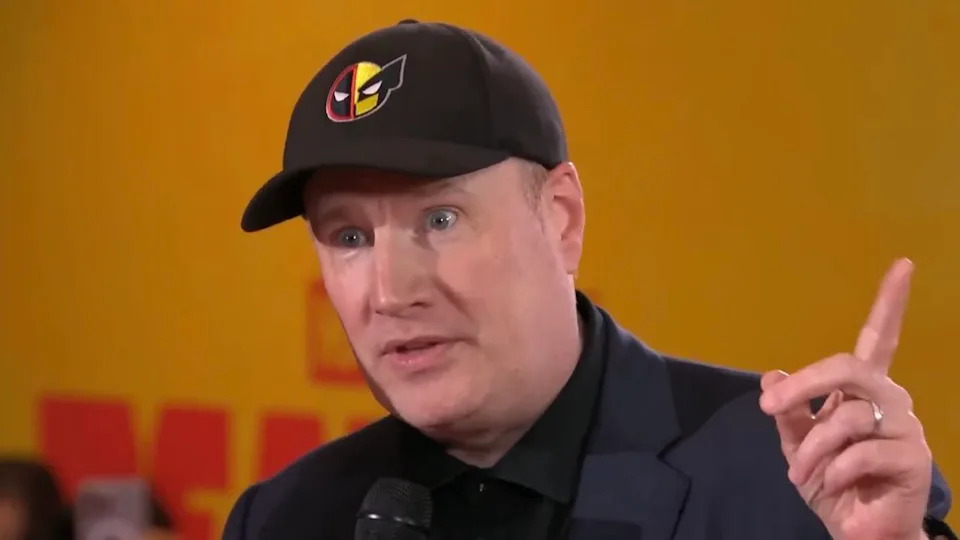  Kevin Feige wearing Deadpool and Wolverine hat and pointing upwards during interview. 