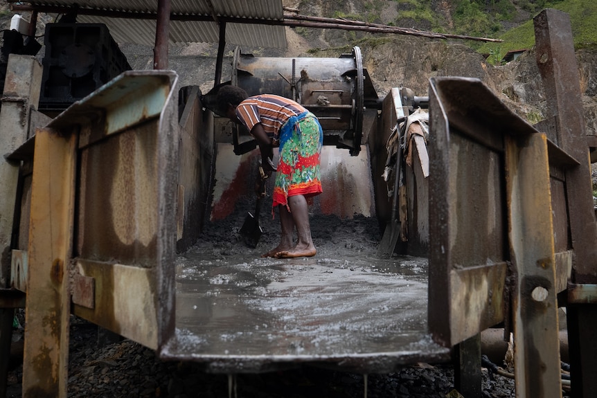 A woman bending down to use some of the machinery at Panguna mine.