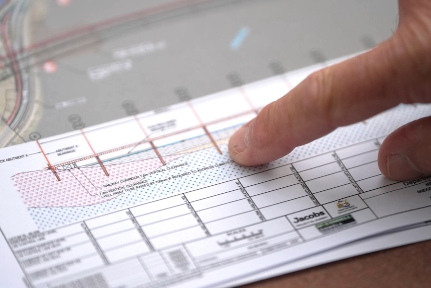 An close up of a bridge design drawing, with an engineer pointing to the piles.