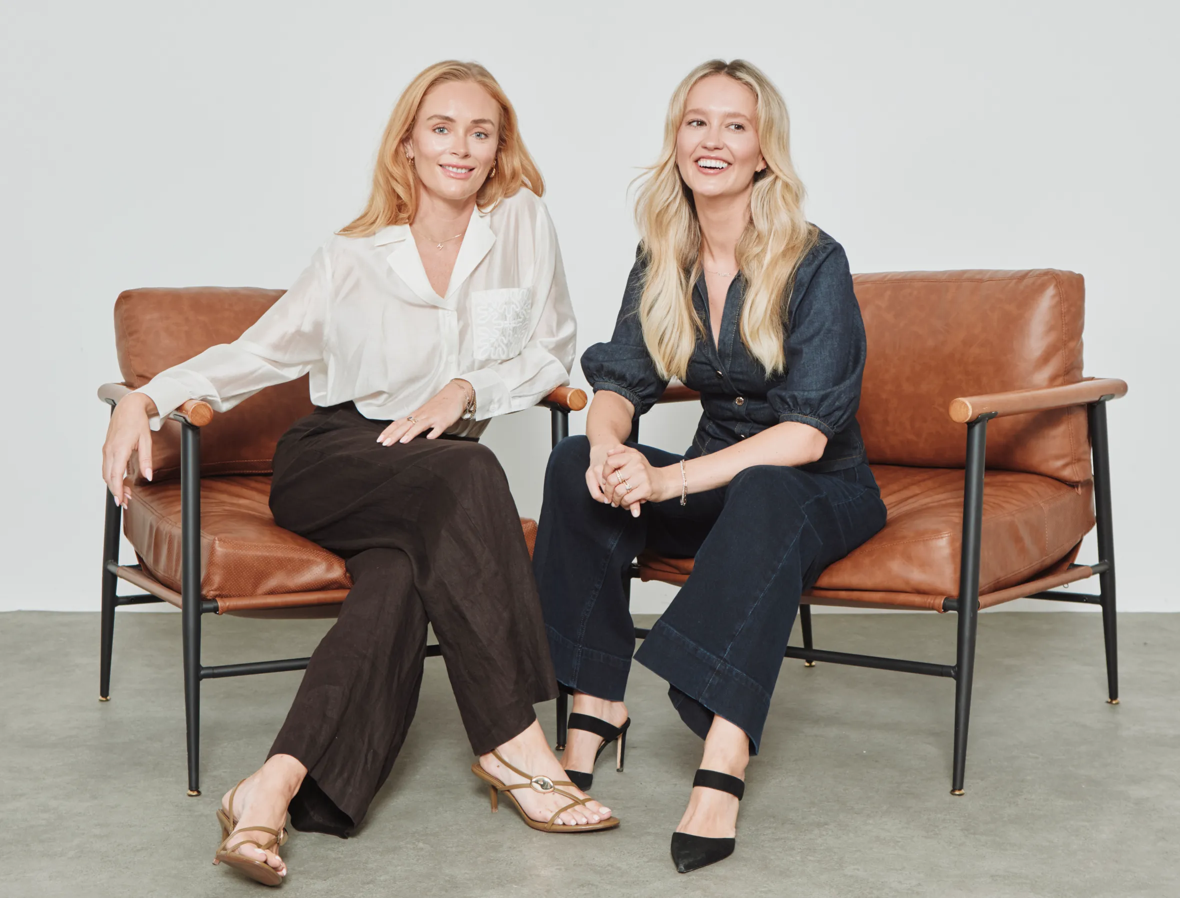 Joely Walker and Holly Brooke seated on brown leather chairs.