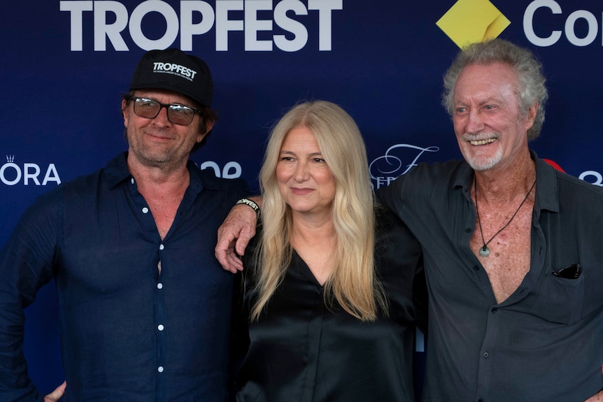 John Polson and Bryan Brown either side of Bruna Papandrea photographed waist-up smiling against a media wall