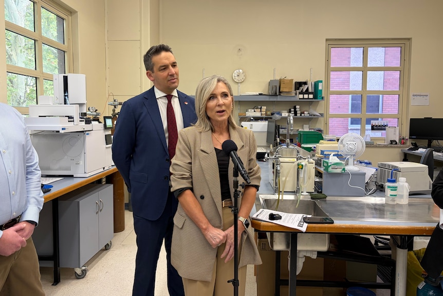 A doctor stands in front of a micraophone