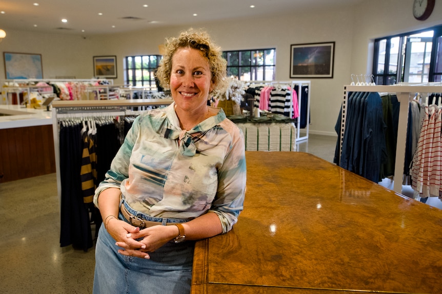 An older woman standing in a clothing store.