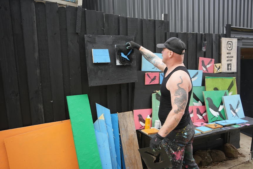Mike Mclean removes a stencil for one of his willie wagtail artworks.