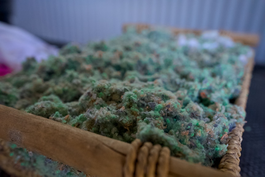 A box of cotton fibres that are green and grey in colour.