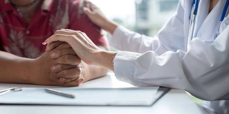 Close-up of doctor holding a patient's hands.