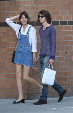 Alexa Chung in a denim pinafore and Alex Turner with long hair, sunglasses and jeans.