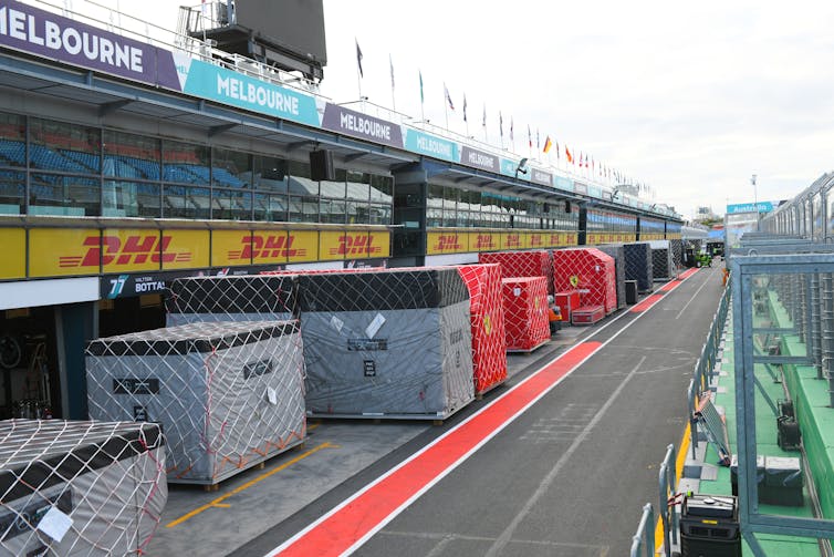 Equipment containers sit alongside a road beneath viewing stands.