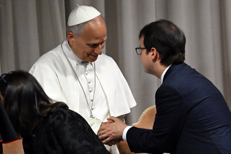 The pope shaking hands with a man in a suit