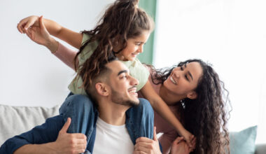 Smiling young parents with their daughter dream of success.