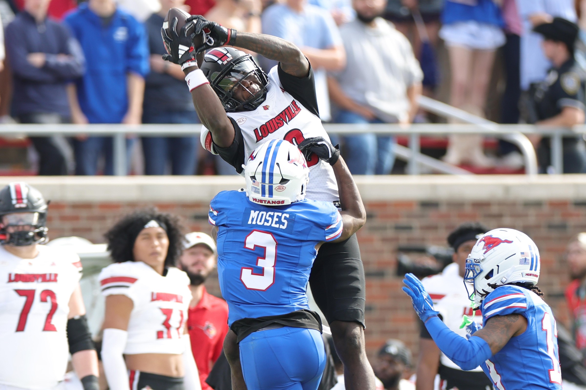 DALLAS, TEXAS - NOVEMBER 22: Chris Bell #0 of the Louisville Cardinals catches a pass in front of Ahmaad Moses #3 of the Southern Methodist University Mustangs during the first half at Gerald J. Ford Stadium on November 22, 2025 in Dallas, Texas. (Photo by Stacy Revere/Getty Images)