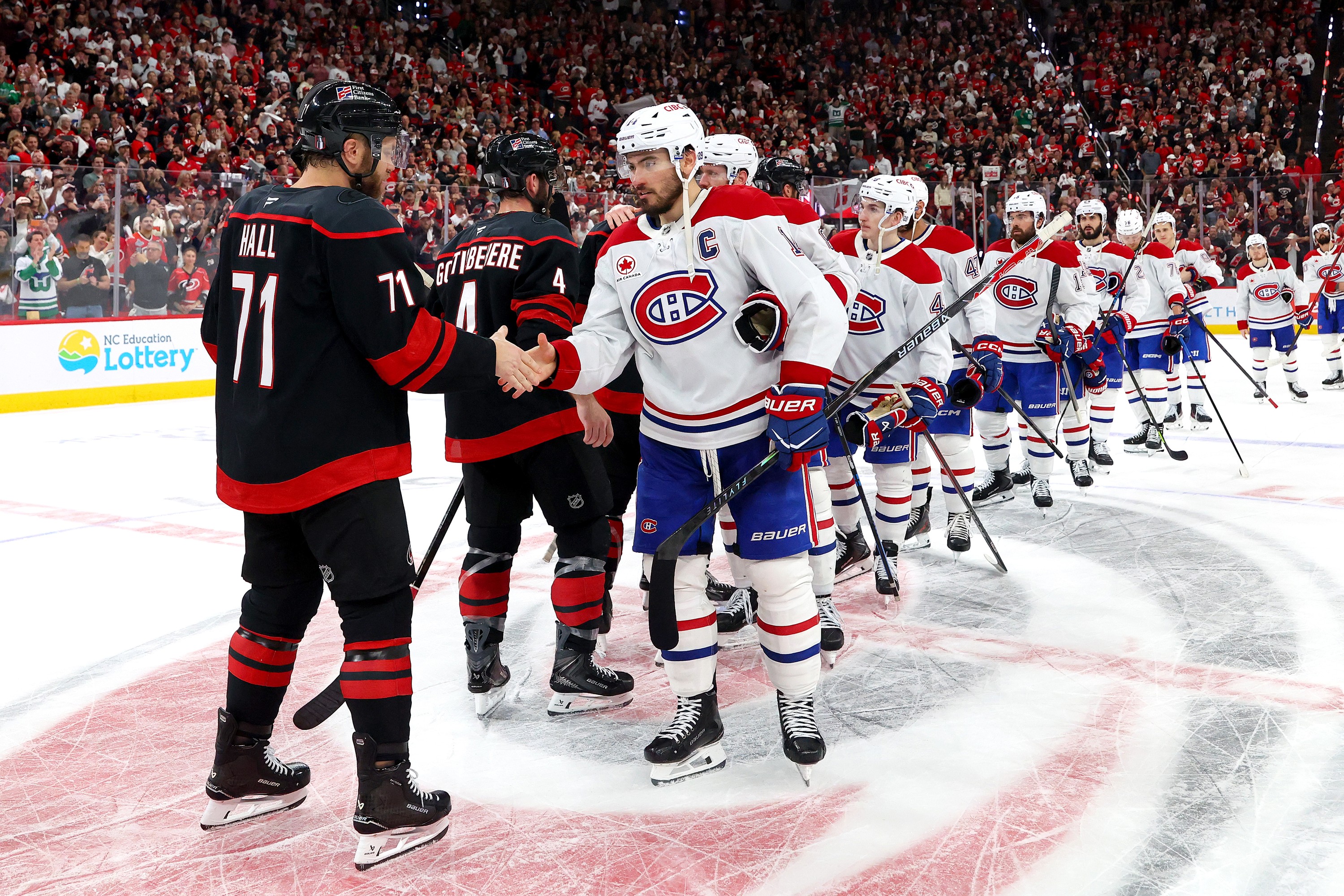 Two hockey teams meet centre ice to shake heads after a playoff series. 