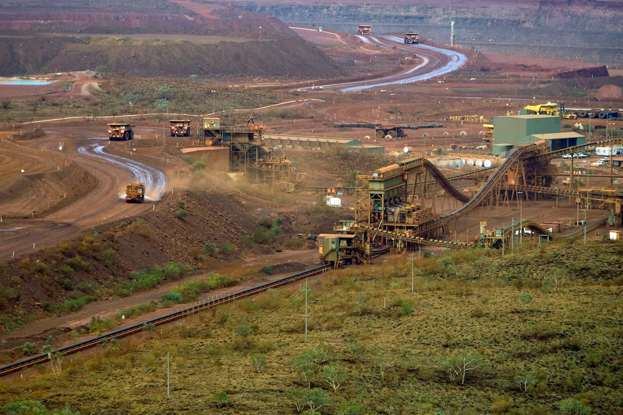Large trucks and mining machinery in an arid landscape.