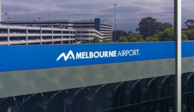 A sign displaying the logo and name of Melbourne Airport beside a parking structure.
