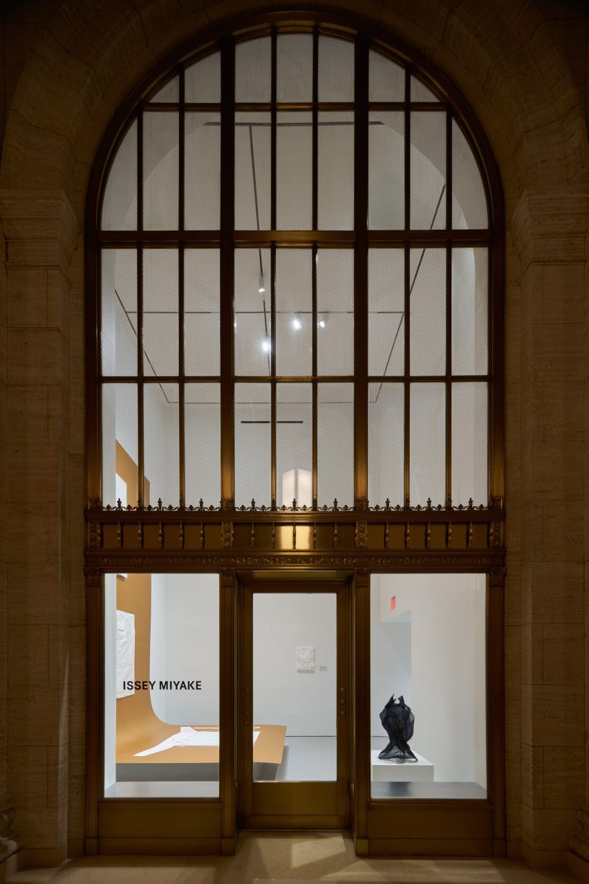 Exterior of a large arched window looking into a white gallery space