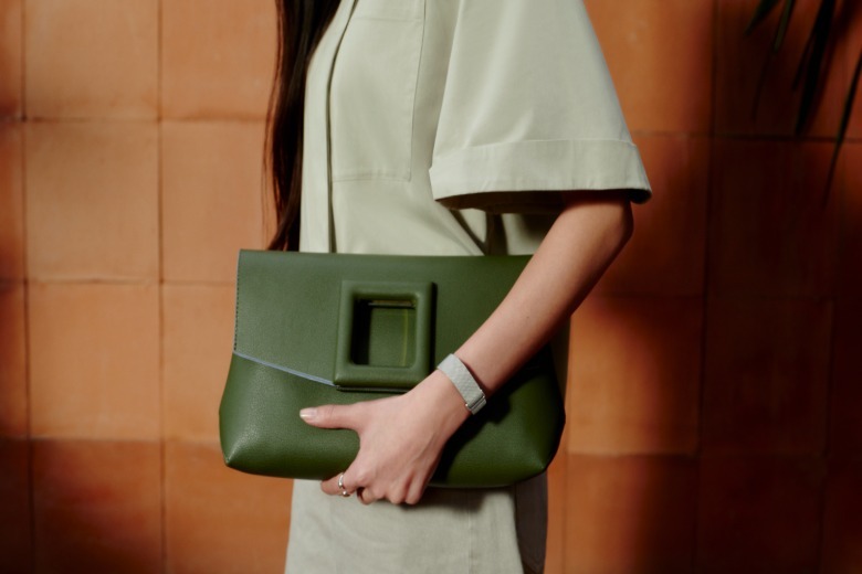The Fitbit Air on a wrist against a green purse.