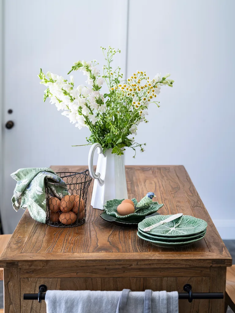 A timber table topped with a basket of eggs and cabbage plates