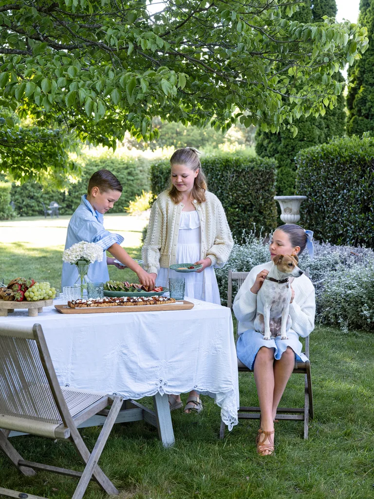 Three kids pick at a fruit platter in their garden
