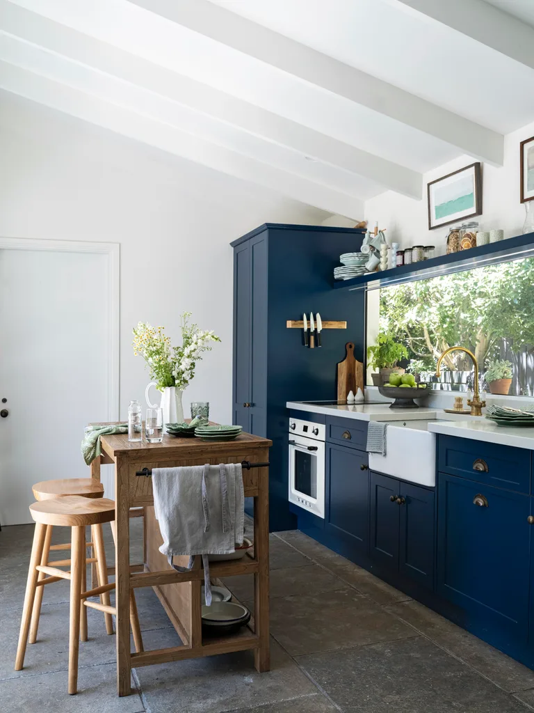 A kitchen with navy blue cabinetry and a timber workbench