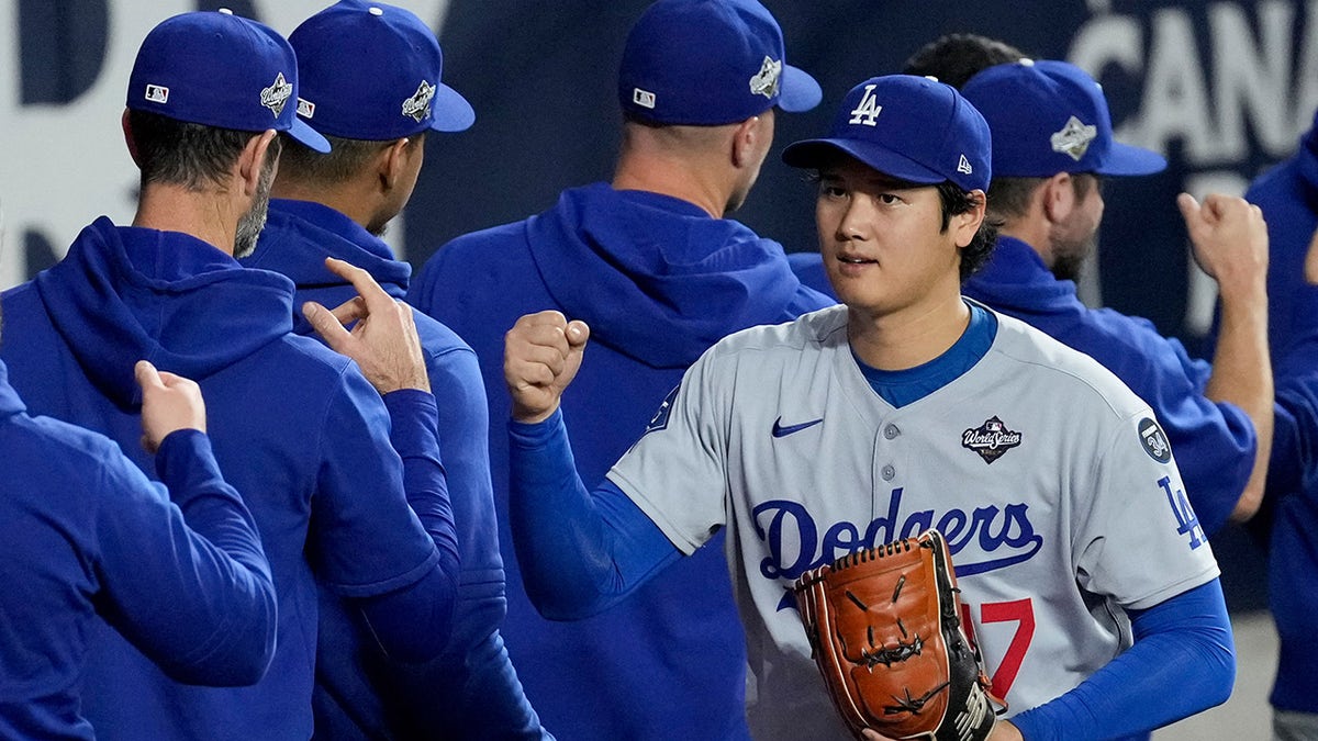 Shohei Ohtani fist bumps teammates in the bullpen before Game 7 of the World Series in Toronto