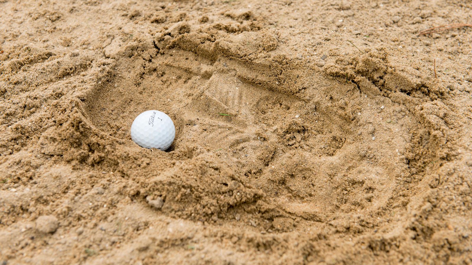 A ball in a footprint in an unraked bunker