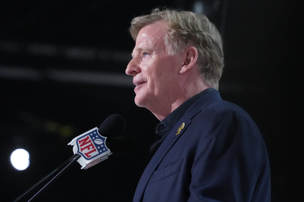 NFL Commissioner Roger Goodell speaks at a microphone with an NFL logo.