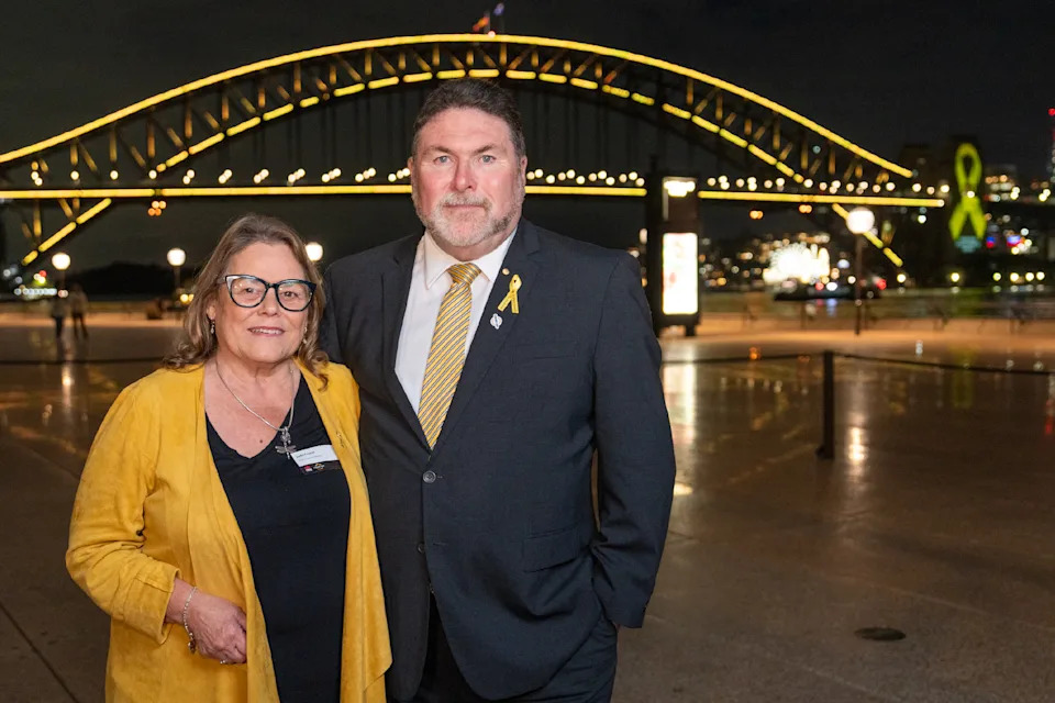 Peter and Judy Frazer standing in front of the Sydney Harbour Bridge.
