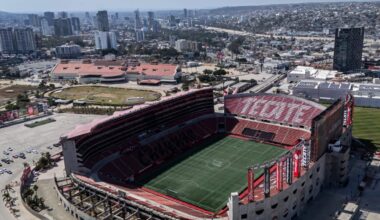 Aerial view of a football stadium with a city skyline behind it.