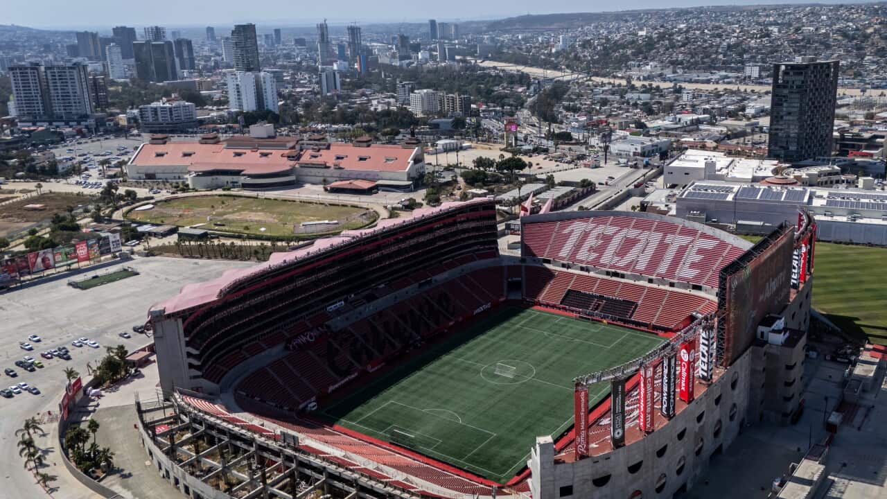 Aerial view of a football stadium with a city skyline behind it.