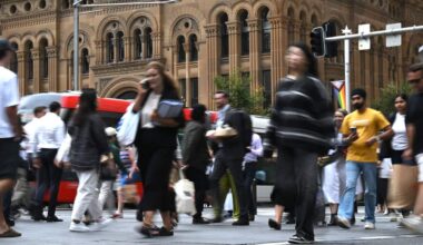 Pedestrians crossing a busy city street in Sydney CBD.