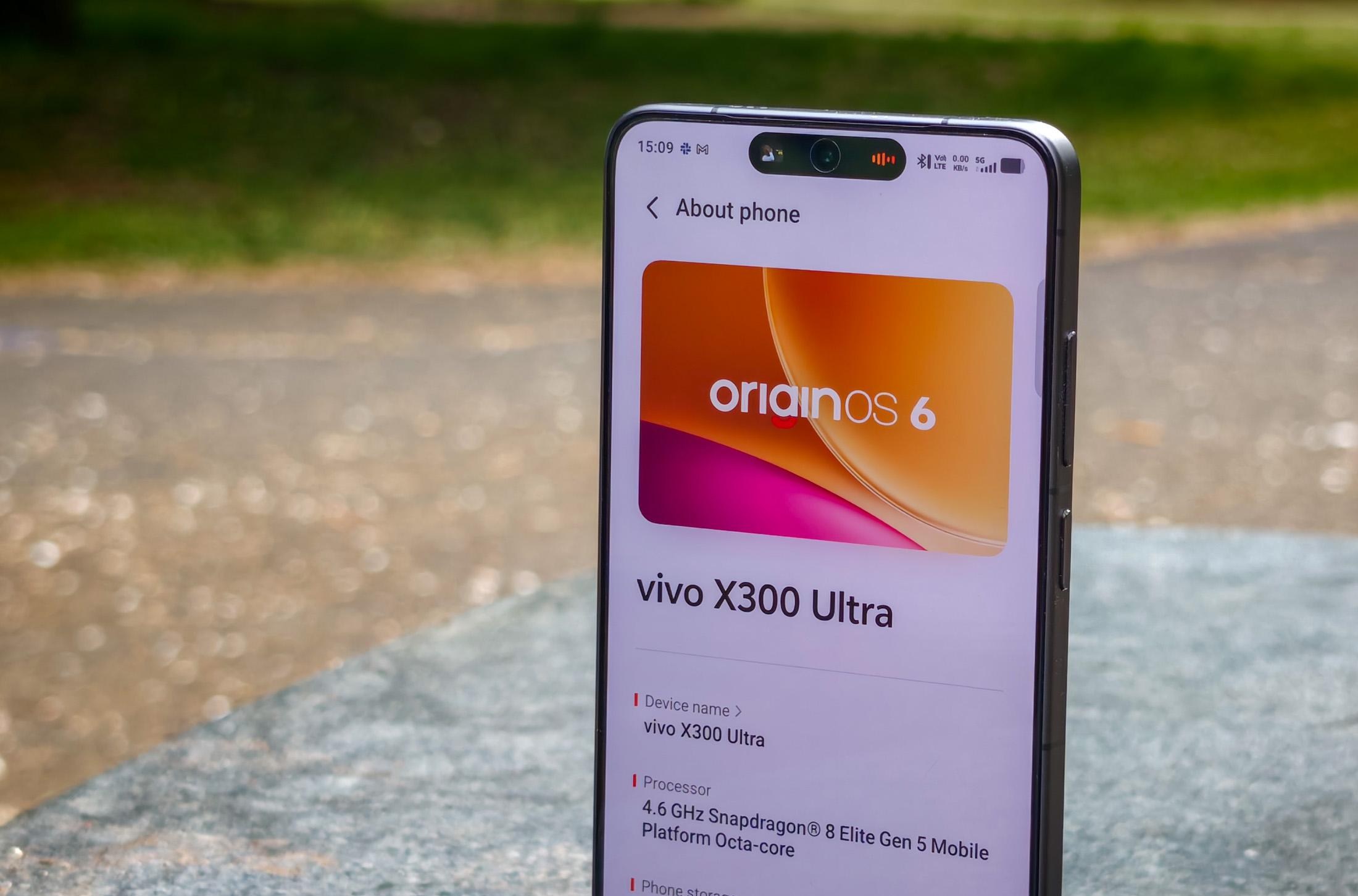 Photo of the Vivo X300 Ultra standing on a gray stone bench showing the OriginOS 6 info screen.