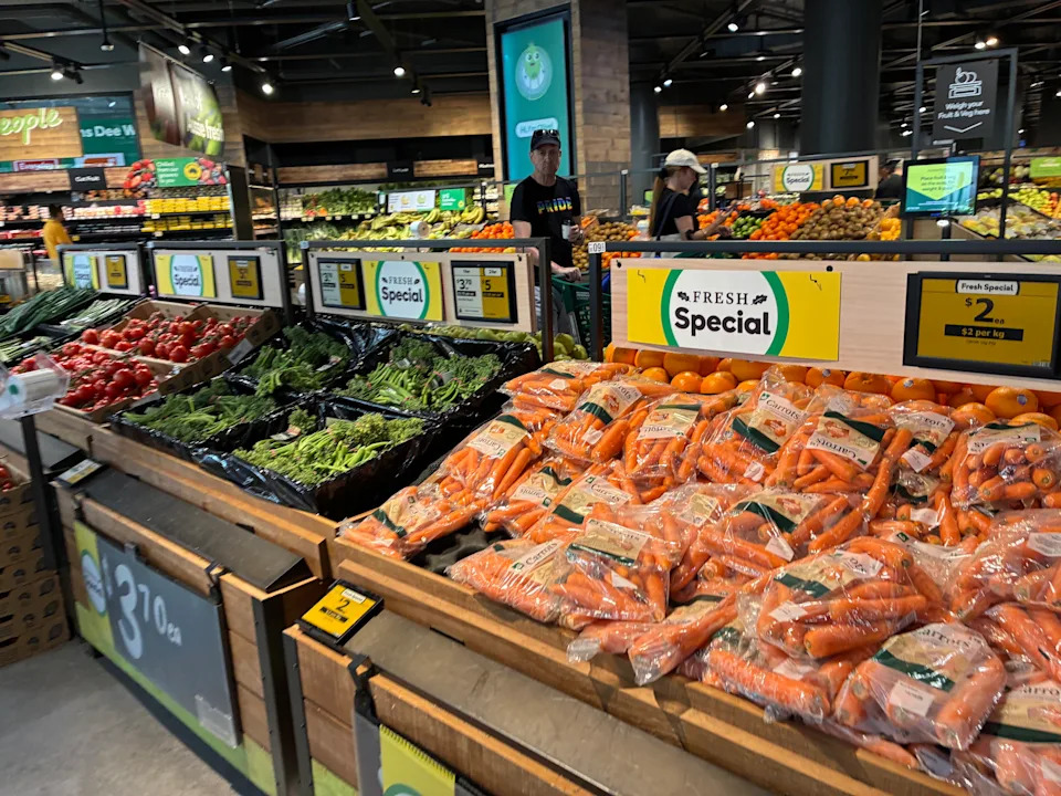 The produce section of Woolworths store showing carrots wrapped in soft plastic.