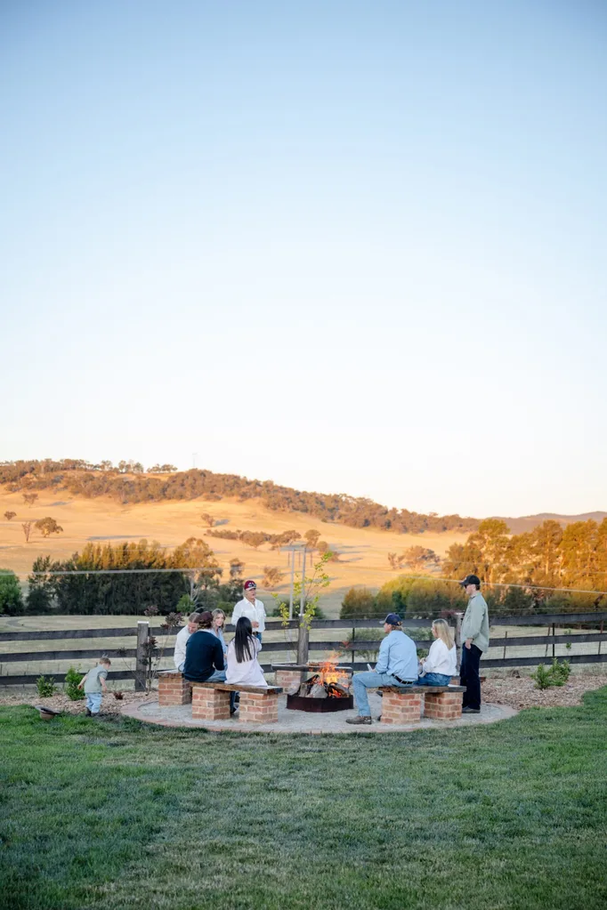 A family sits around a fire pit on their country property