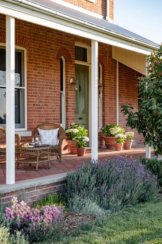 The verandah of a red brick homestead with rattan chairs