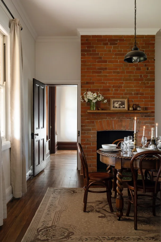 A dining room with a red brick fireplace