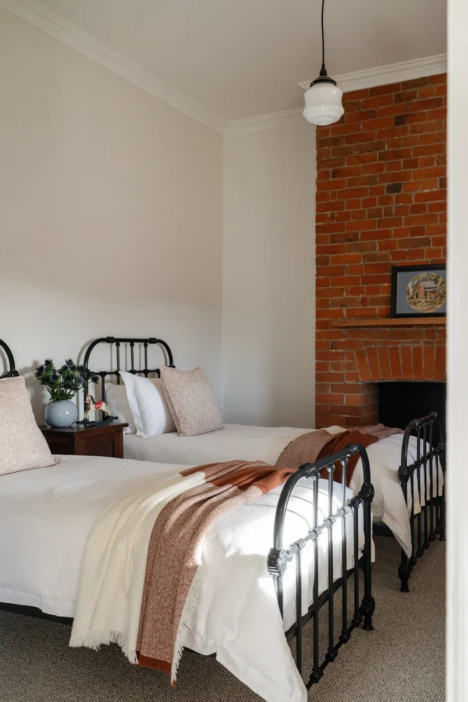 A bedroom with twins beds and a red brick fireplace