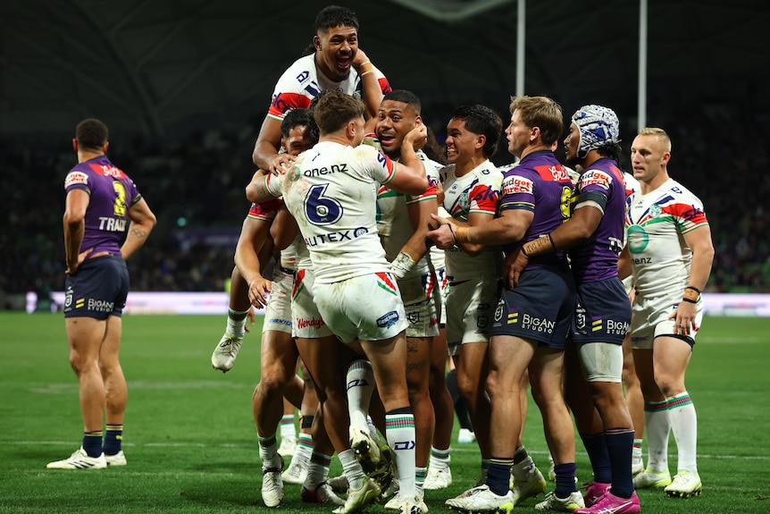 A group of rugby league players celebrate winning a game