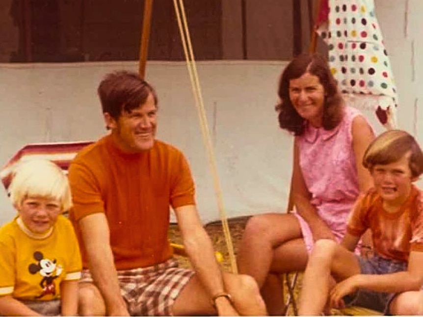 1970s photograph mum dad and two sons sitting outside in yard.