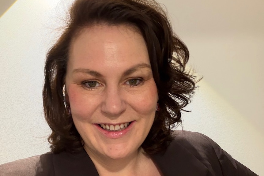 A dark-haired woman smiles for a selfie.