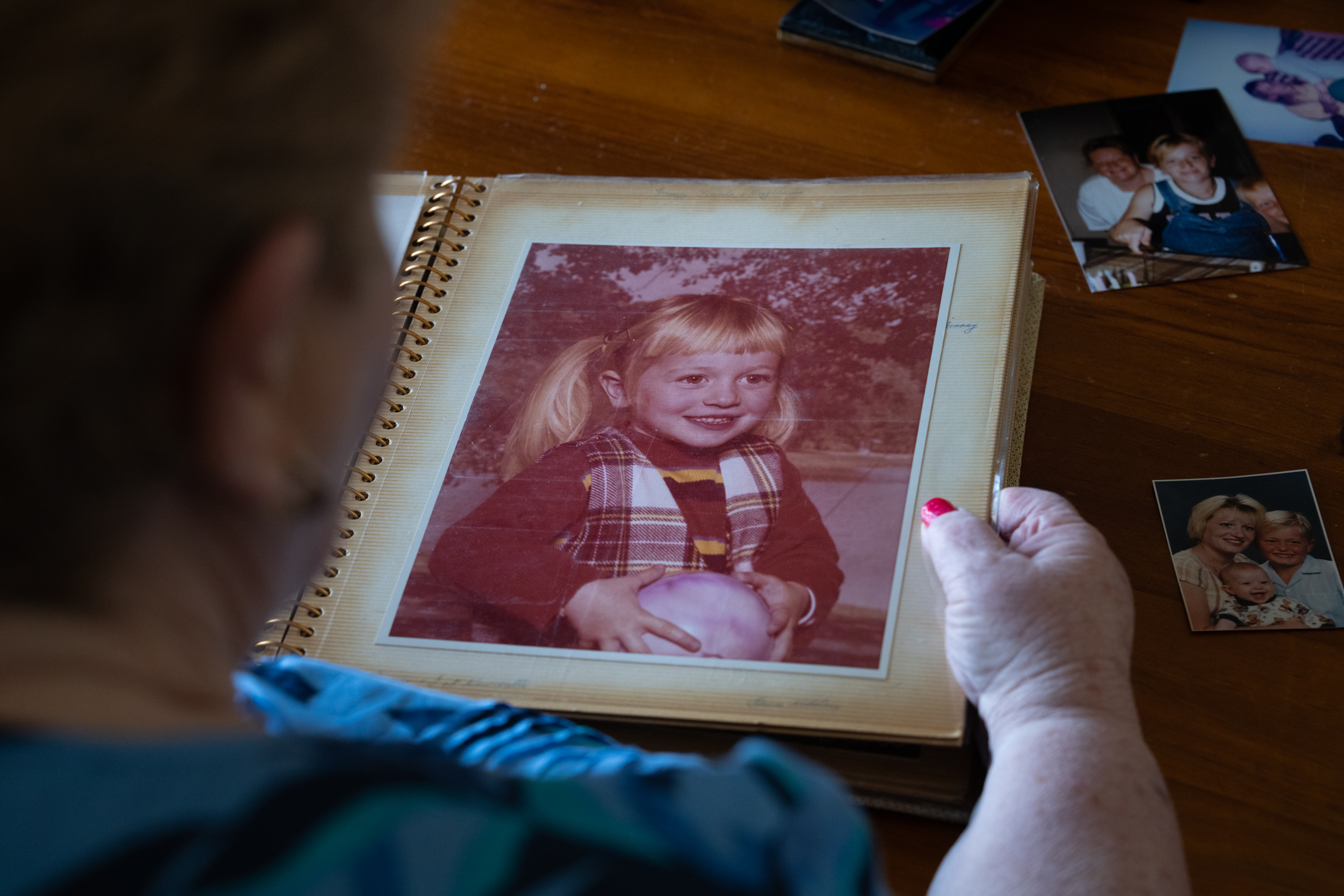 A woman looks at a photo of a child with long blonde pigtails.