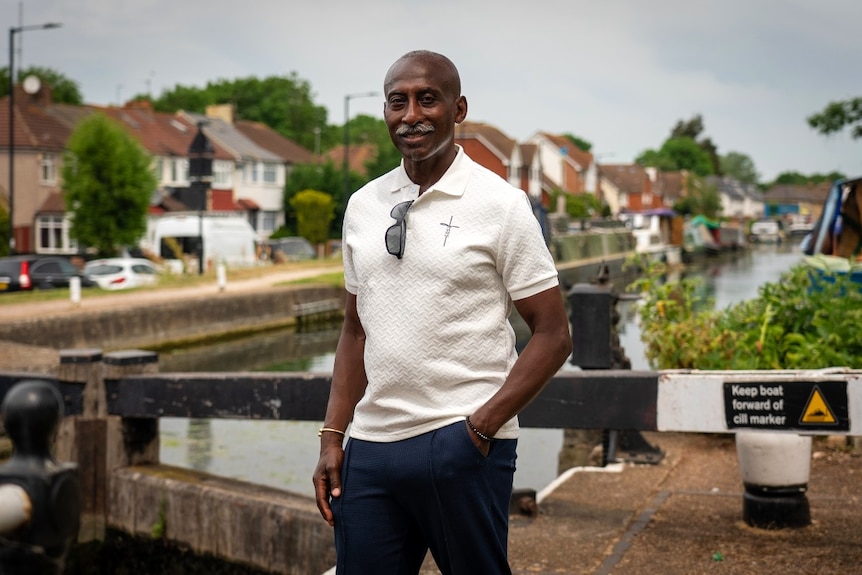 A man standing near a canal, smiling at the camera.