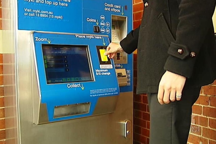 Man pays for a train fare at an old myki ticket machine.