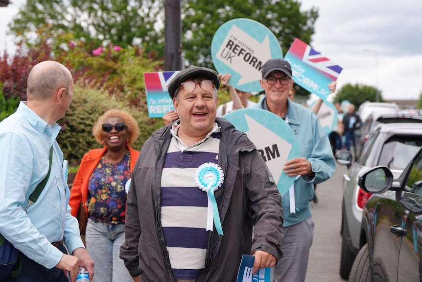 A group of people holding political signs, walking and smiling.