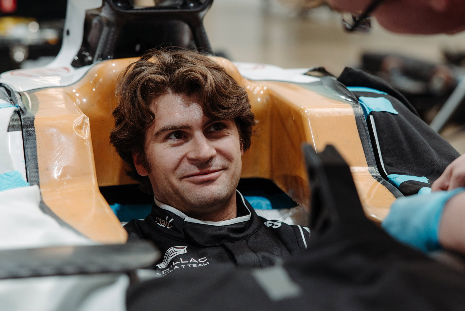 Colton Herta sitting in the cockpit of a Cadillac F1 car with a smile on his face