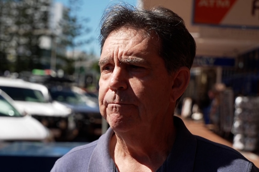 A man wearing a polo shirt standing on a coastal street